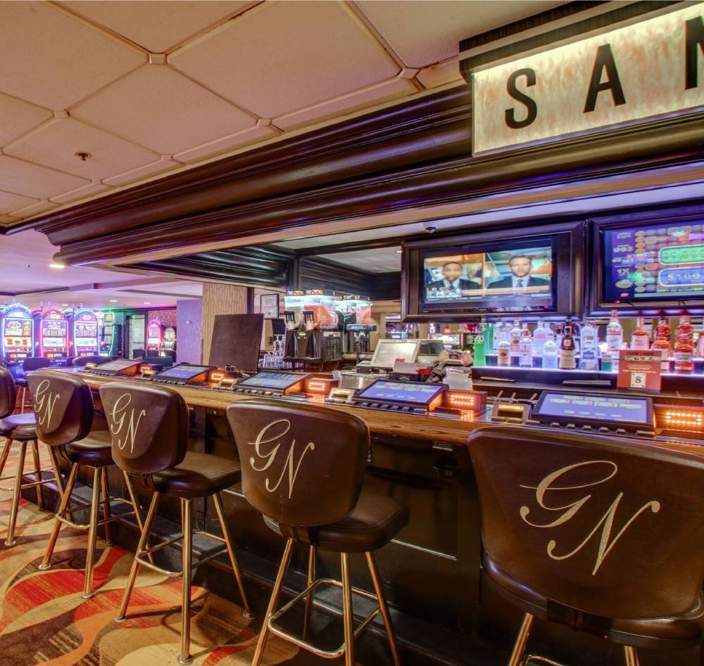 A bar with chairs and a television on the wall.